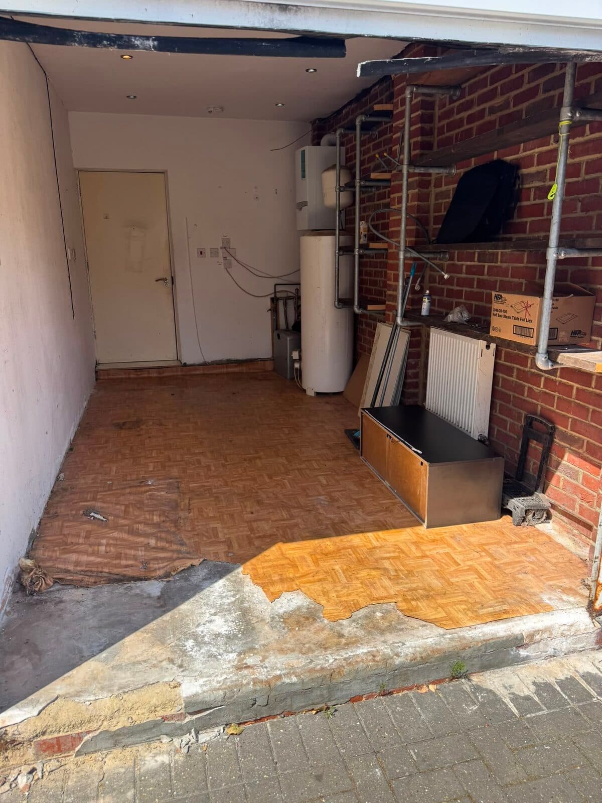 Room mid-renovation with the floor lifted and wall back to brick, worked around during the Luton two-bedroom move