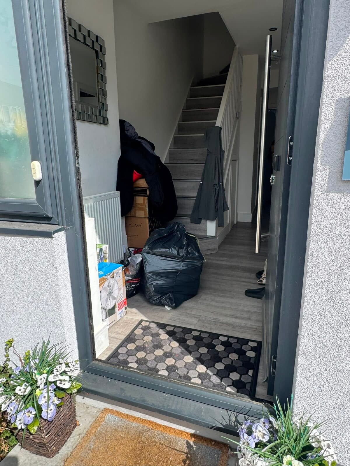 Front door open at the Uxbridge property with bagged items staged in the hallway ready to carry out