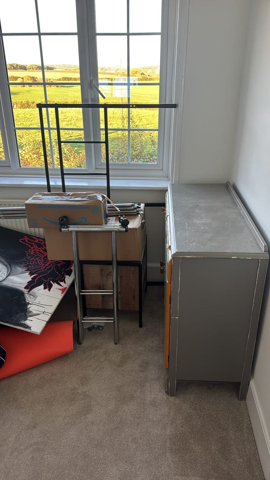 Bedroom corner with boxes, artwork and dismantled bed parts staged for carrying out