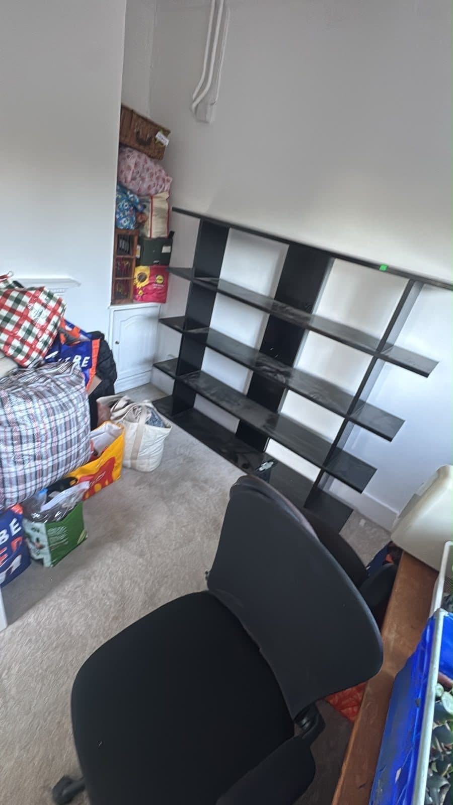 Shelving unit, office chair and packed bags waiting to be loaded from an upstairs room