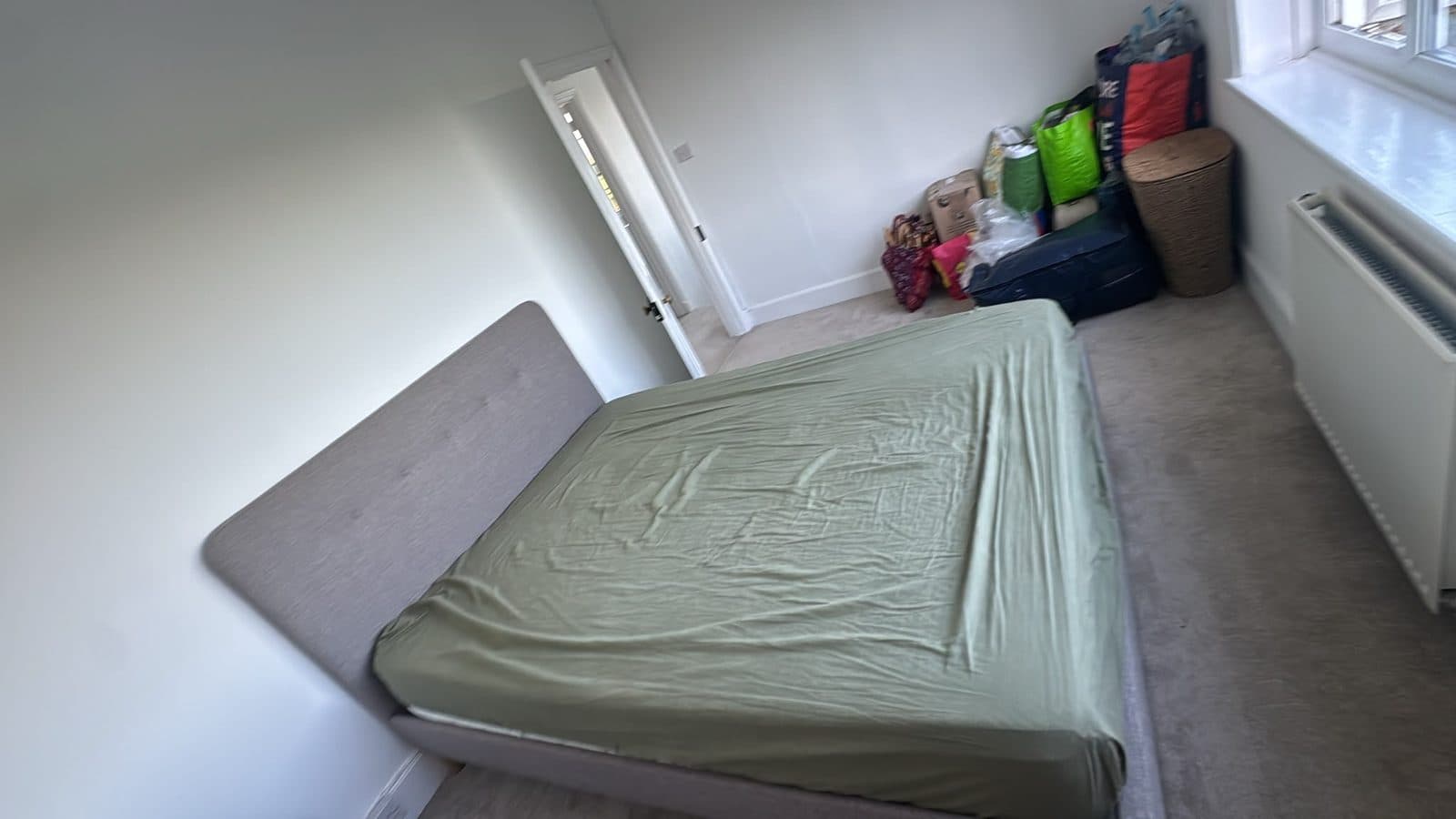 Upholstered bed frame and mattress in a first-floor bedroom ahead of the move