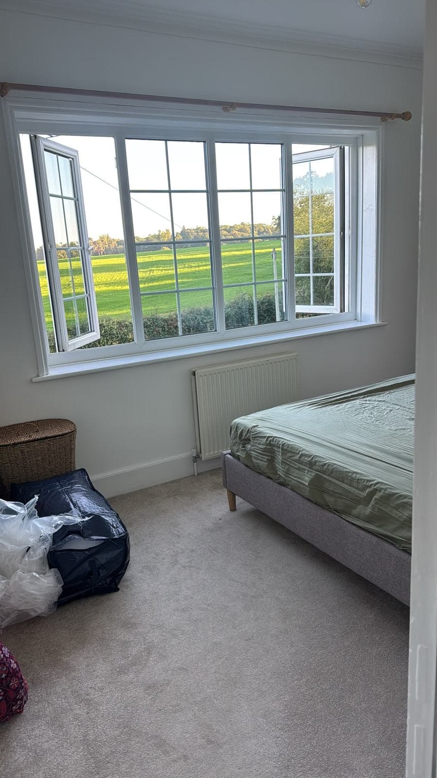 Bedroom with the windows open onto the fields, cleared down to the bed