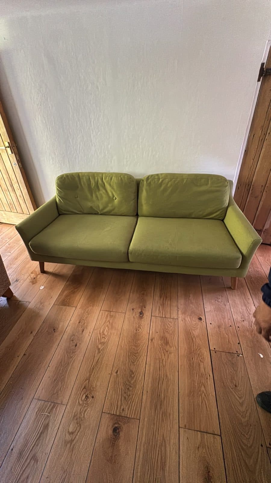 Green sofa set down in a wood-floored room at the new property