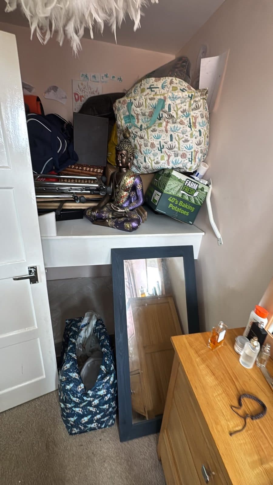 Bedroom alcove packed up — bags, boxes, a leaning mirror and a chest of drawers ready to go