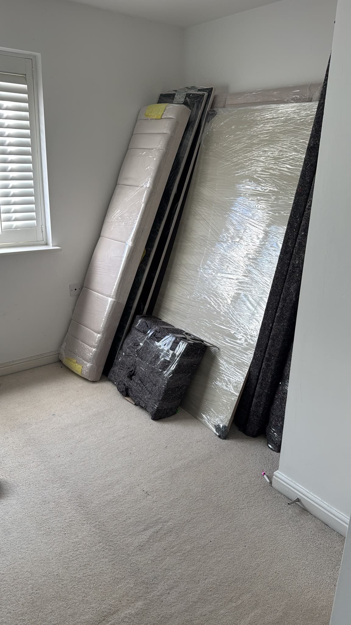 Wrapped mattresses and bed base stacked against the wall ready for the move