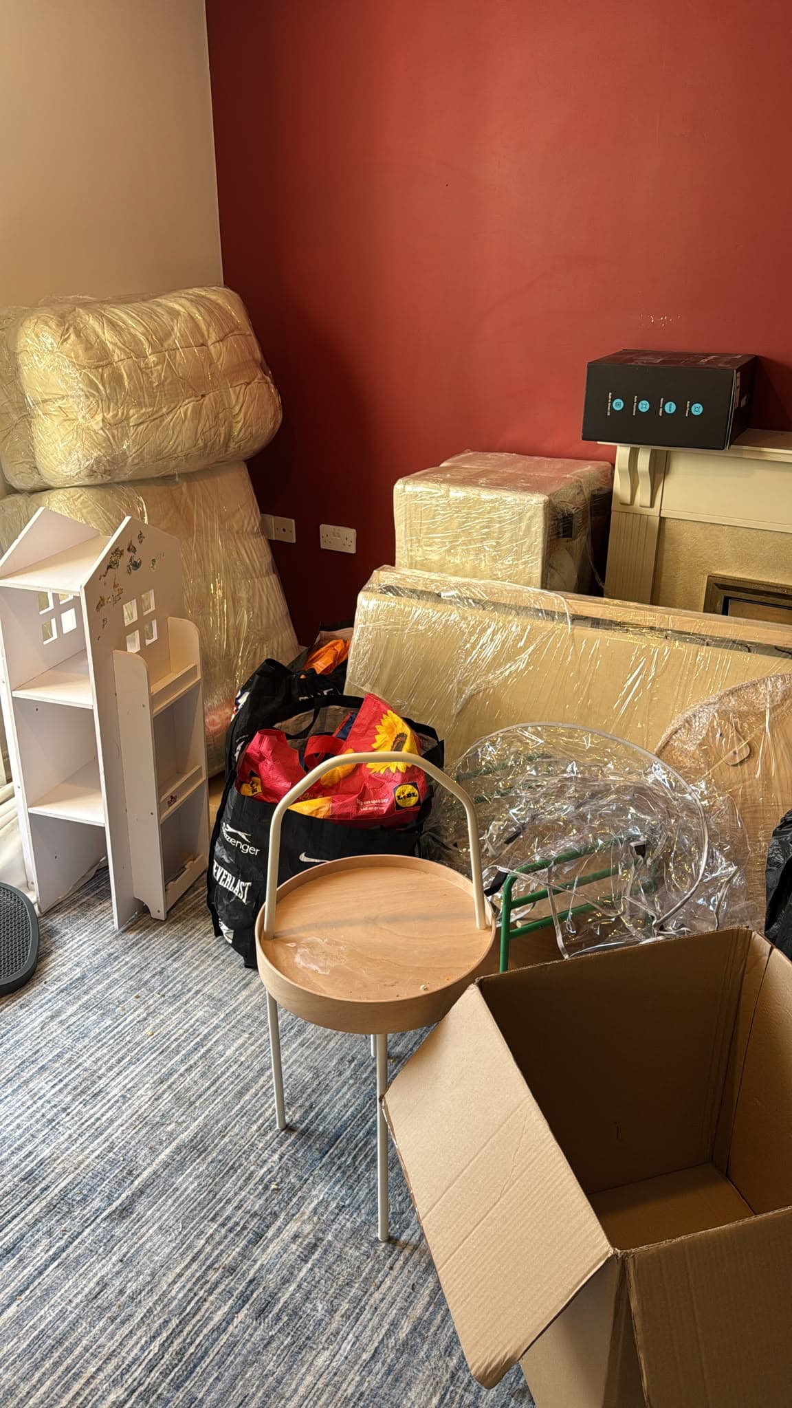 Wrapped furniture, shelving and boxes gathered in the living room ahead of the move