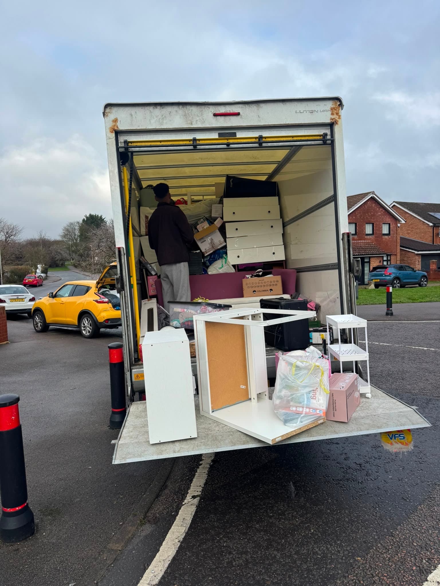A RayMovals mover loading furniture onto the van's tail-lift during a house removal